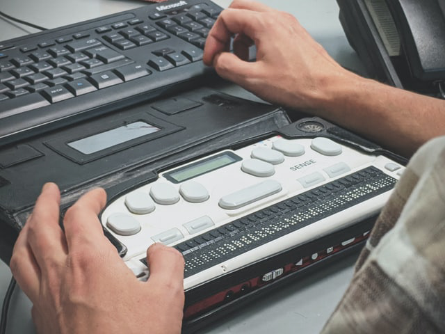 Person using a Braille writer (Photo by Sigmund on Unsplash)